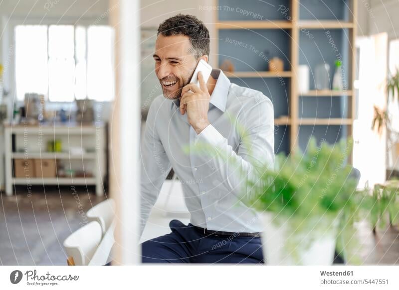 Happy businessman in office on cell phone mobile phone mobiles mobile phones Cellphone cell phones laughing Laughter Businessman Business man Businessmen