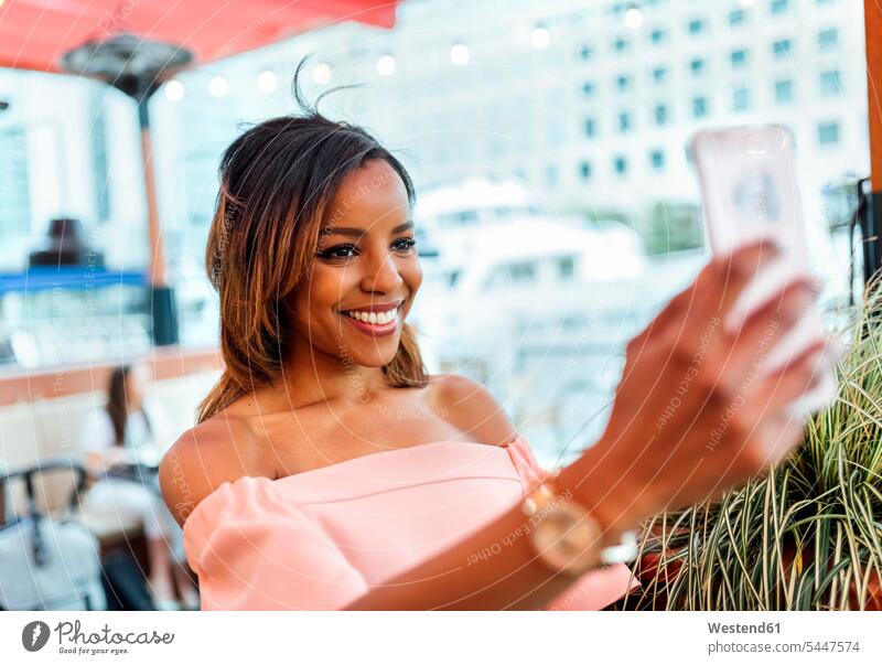 Smiling woman taking a selfie in the city females women smiling smile Selfie Selfies mobile phone mobiles mobile phones Cellphone cell phone cell phones Adults