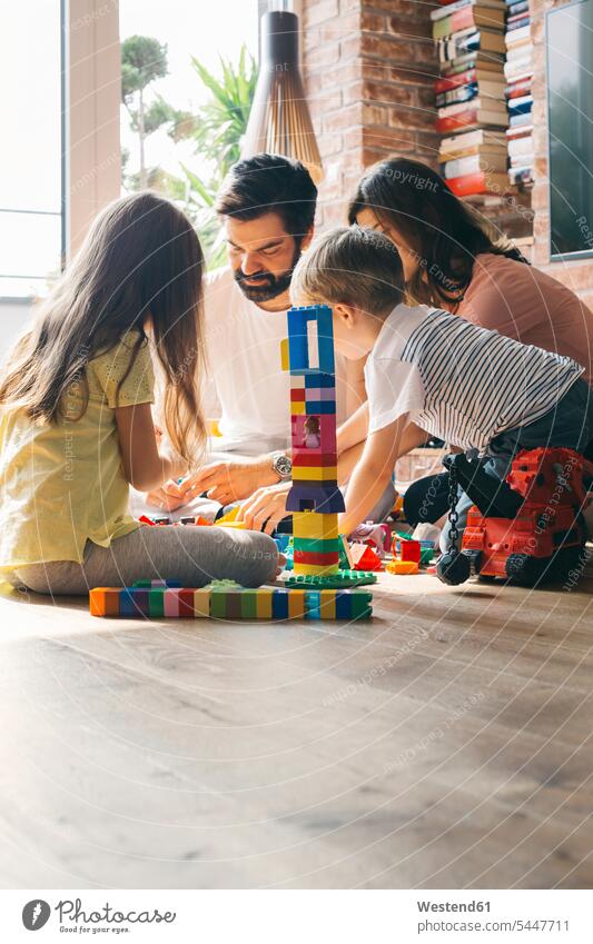 Family playing with building blocks on the floor together family families people persons human being humans human beings home at home four people 4