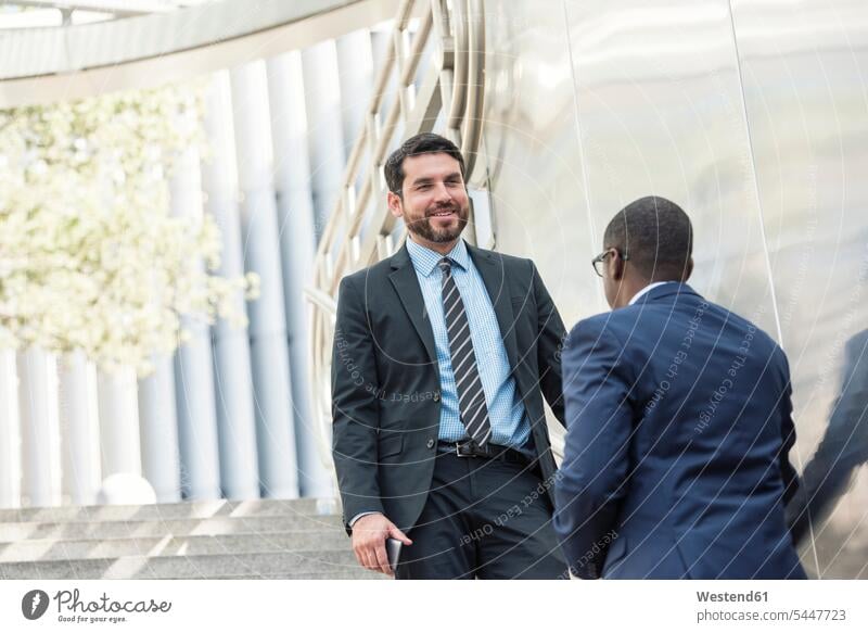 Two businessmen talking outdoors Businessman Business man Businessmen Business men speaking smiling smile colleagues business people businesspeople