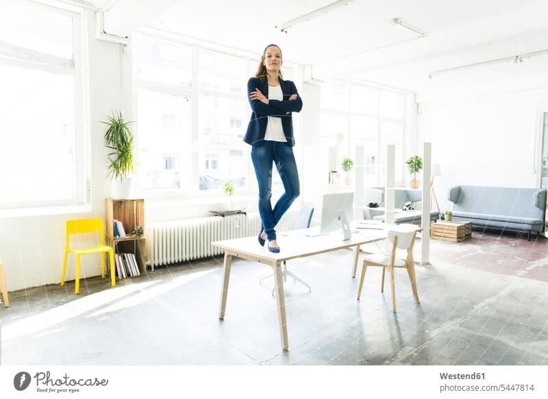 Portrait of businesswoman standing on table in a loft businesswomen business woman business women desk desks females business people businesspeople