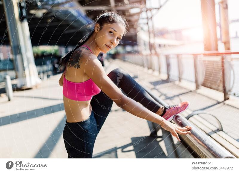 Woman doing stretching exercises in Manhattan near Brooklyn Bridge in the morning woman females women exercising training practising practicing practice