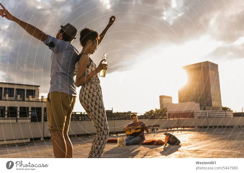 Young couple dancing on a rooftop party friends roof terrace deck dance Beer Beers Ale drinking Fun having fun funny celebrating celebrate partying Party