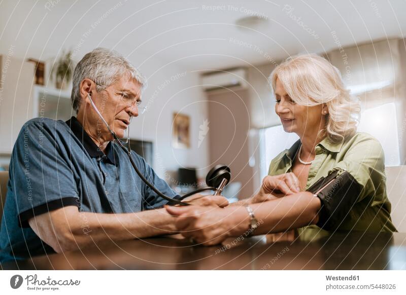 Senior couple taking blood pressure twosomes partnership couples senior men senior man elder man elder men senior citizen illness disease Sickness illnesses