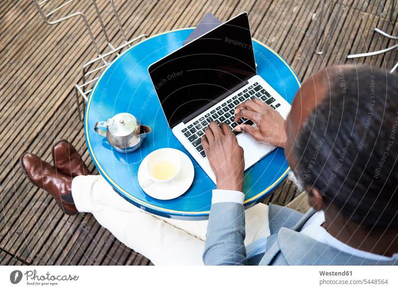 Businessman sitting on terrace using laptop Business man Businessmen Business men Laptop Computers laptops notebook business people businesspeople