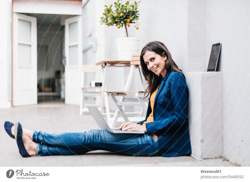 Smiling businesswoman using laptop on the floor Laptop Computers laptops notebook attractive beautiful pretty good-looking Attractiveness Handsome females women