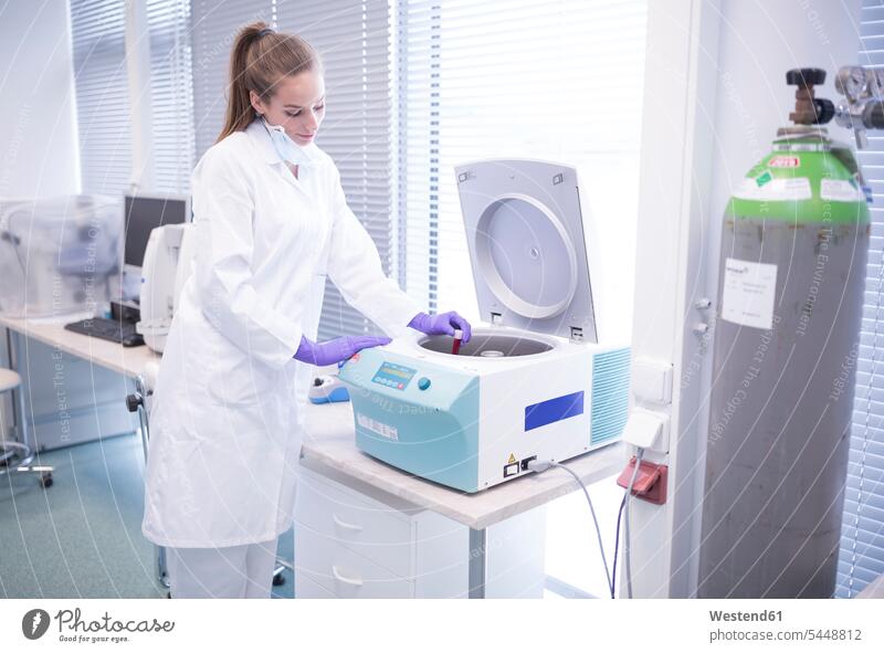 Scientist in lab putting blood sample into centrifuge scientist female scientists examining checking examine swatch Swatches Samples laboratory science sciences