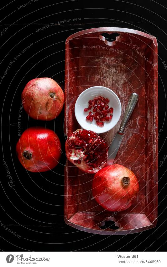 Whole pomegranate and pomegranate seed with bowl and knife on wooden tray food and drink Nutrition Alimentation Food and Drinks half halves halved overhead view