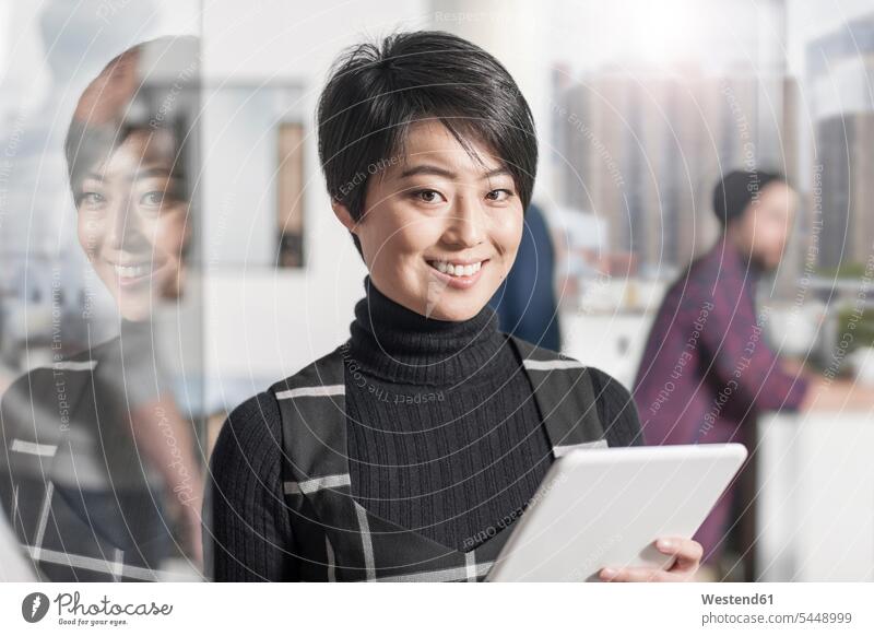 Portrait of smiling woman holding a tablet in office offices office room office rooms portrait portraits females women digitizer Tablet Computer Tablet PC
