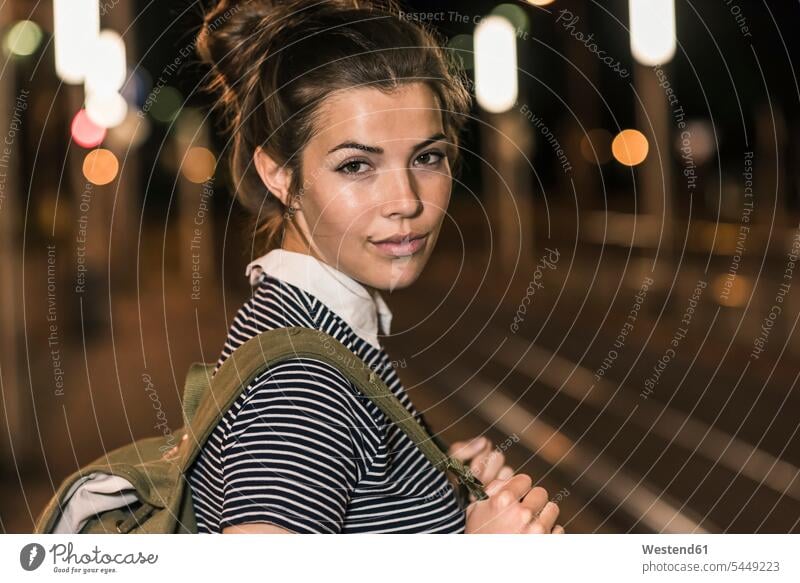 Portrait of young woman with backpack waiting at station by night portrait portraits at night nite night photography females women Adults grown-ups grownups