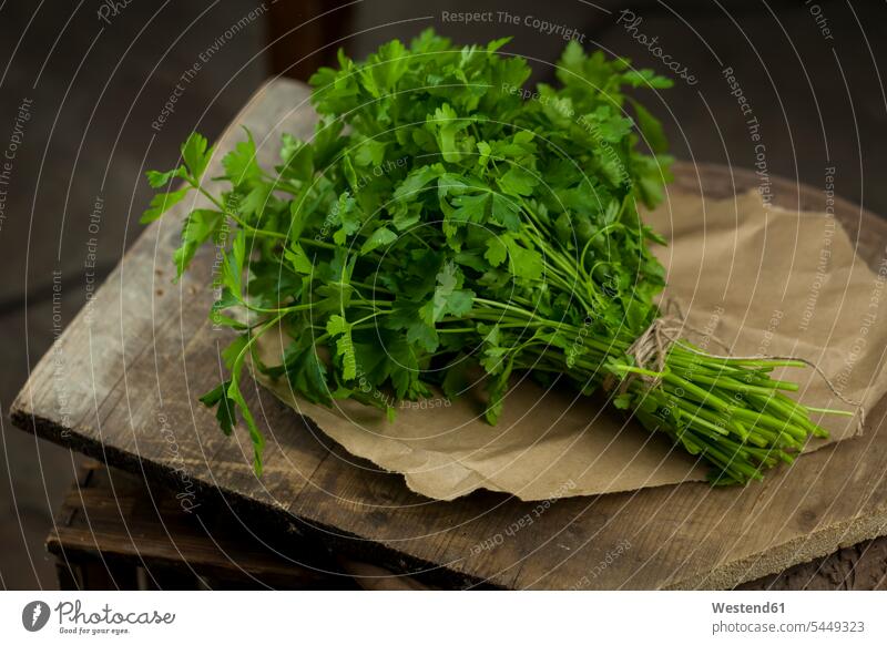 Bunch of flat leaf parsley on brown paper and wood close-up close up closeups close ups close-ups nobody tied tied up green wooden board wooden boards