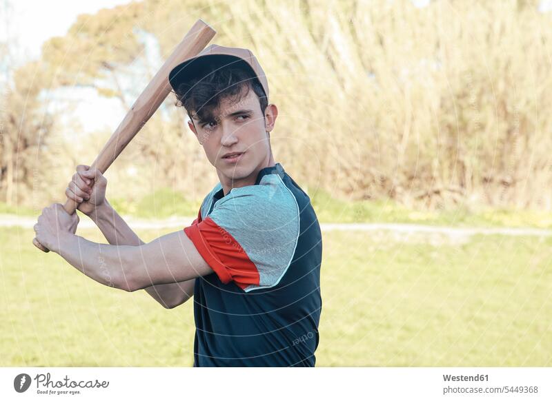 Portrait of young man with baseball bat in park baseball player baseball players men males Bat Sports Bat sport sports Adults grown-ups grownups adult people