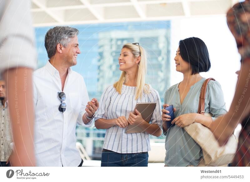 Group of casual businesspeople socializing on urban square mobile phone mobiles mobile phones Cellphone cell phone cell phones colleagues smiling smile