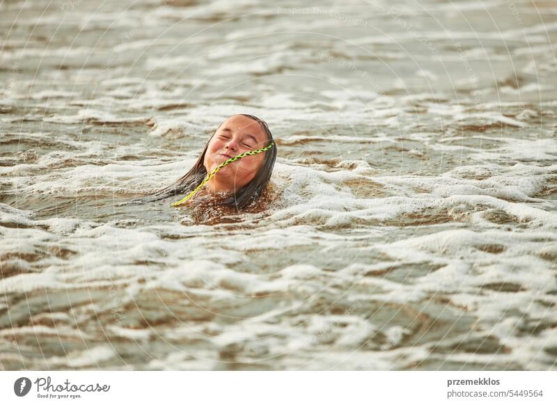 Little girl playing with waves in the sea. Kid playfully splashing in waves. Child jumping in sea. Vacations on the beach. Water splashes summer vacations ocean