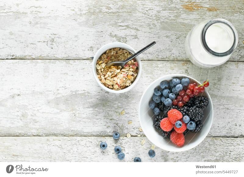 Bowl of granola, milk bottle and bowl of berries on wood Berry berry fruits Berries vitamines Granola Muesli cereals fruit muesli Raspberry Raspberries