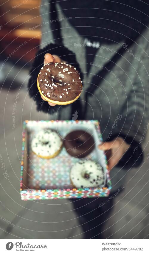 Woman holding doughnut with chocolate icing, partial view donuts Doughnuts Pastry Pastries Sweet Food sweet foods food and drink Nutrition Alimentation