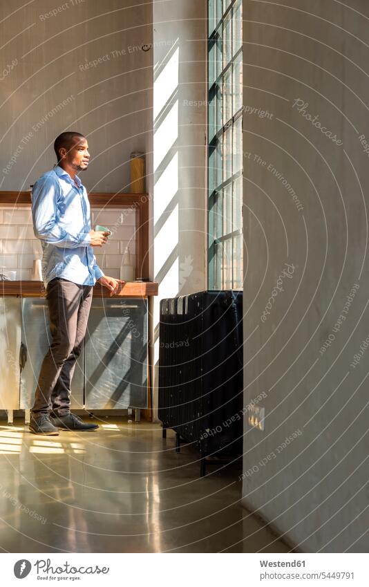 Young entrepreneur standing in company kitchen, drinking coffee young business people businesspeople Coffee Taking a Break resting break young entrepreneur