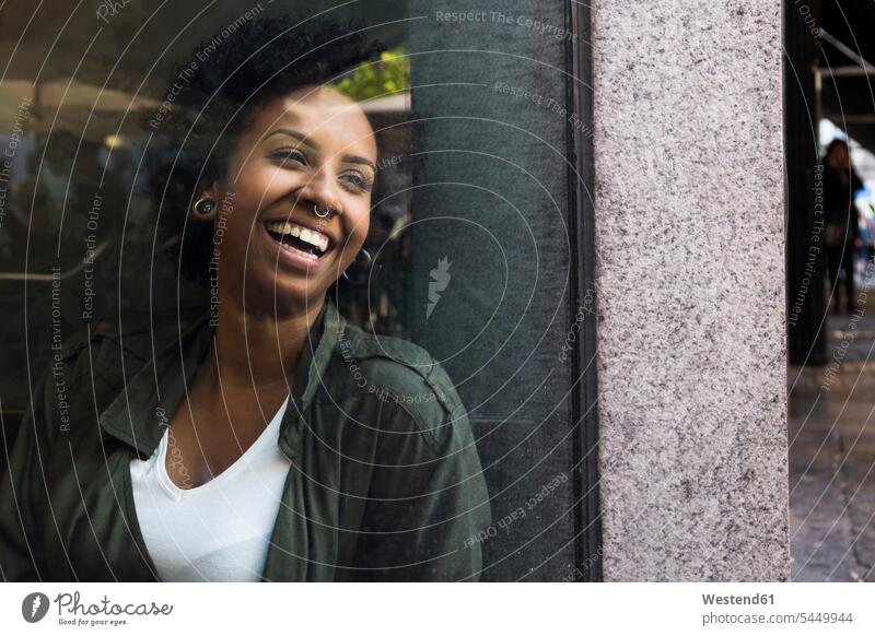 Portrait of laughing young woman looking through window of a cafe females women windows portrait portraits Adults grown-ups grownups adult people persons