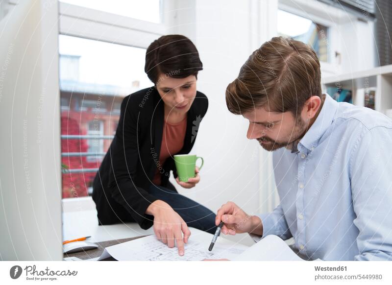 Colleagues working together at desk in office colleagues offices office room office rooms At Work workplace work place place of work business business world