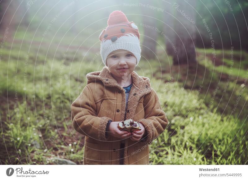 Portrait of boy eating Berliner in forest woolly hat Wooly Hat Knit-Hat Knit Hats wool cap smiling smile one person 1 one person only only one person boys males