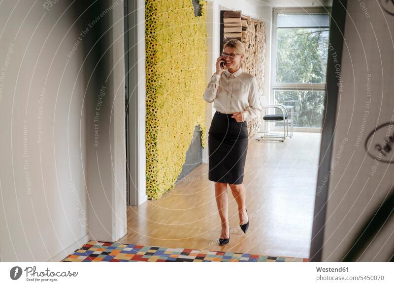 Smiling businesswoman on cell phone on office floor smiling smile on the phone call telephoning On The Telephone calling businesswomen business woman