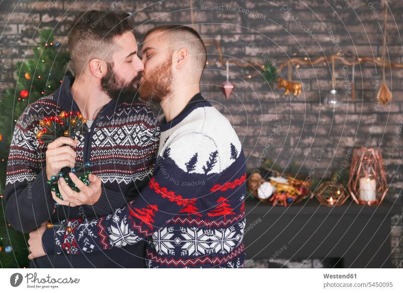 Kissing gay couple with chain of lights at Christmas time at home kissing kisses X-Mas yule Xmas X mas Gay Couple Gays celebration Red-Letter Day Festive Day