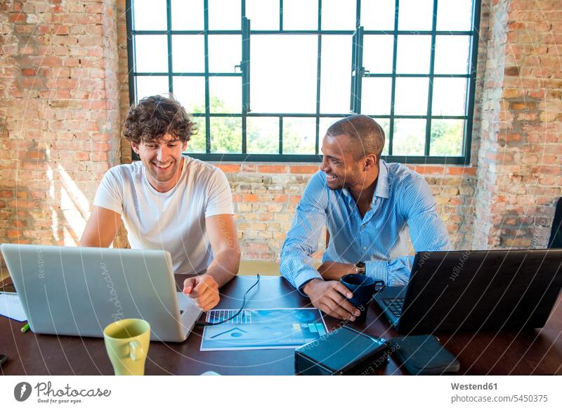 Two young businessmen working together in co-working space, using laptops Planning planning planned business people businesspeople startup start up