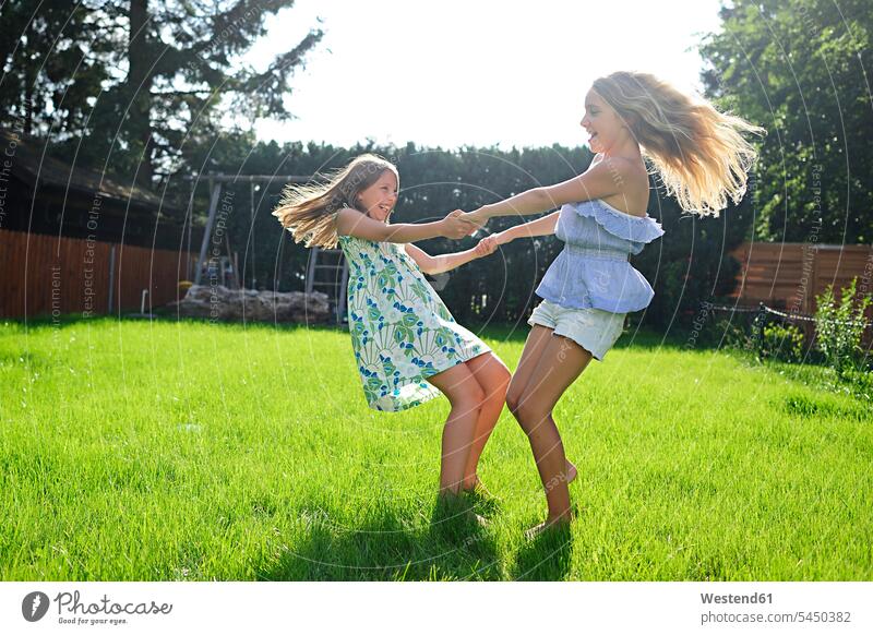 Two happy playful girls in garden female friends playing happiness gardens domestic garden turning females mate friendship child children kid kids people