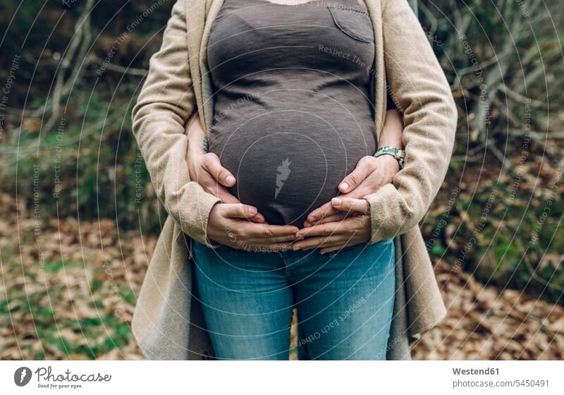 Man holding belly of pregnant woman in nature Pregnant Woman bellies abdomen human abdomen couple twosomes partnership couples people persons human being humans