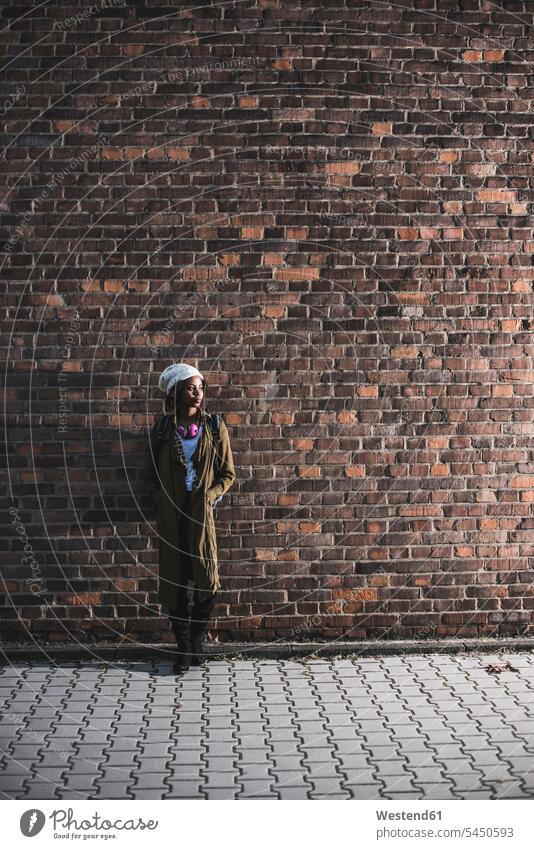 Young woman standing in front of brick wall females women Adults grown-ups grownups adult people persons human being humans human beings headphones headset