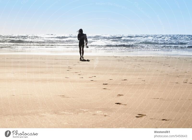 Portugal, Algarve, man on the beach with surfboard surfing surf ride surf riding Surfboarding surfboards beaches walking going water sports Water Sport aquatics