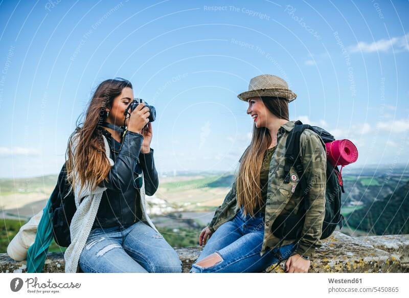 Two happy young women on a trip taking a photo female friends camera cameras photographing mate friendship female tourist woman females tourists tourism