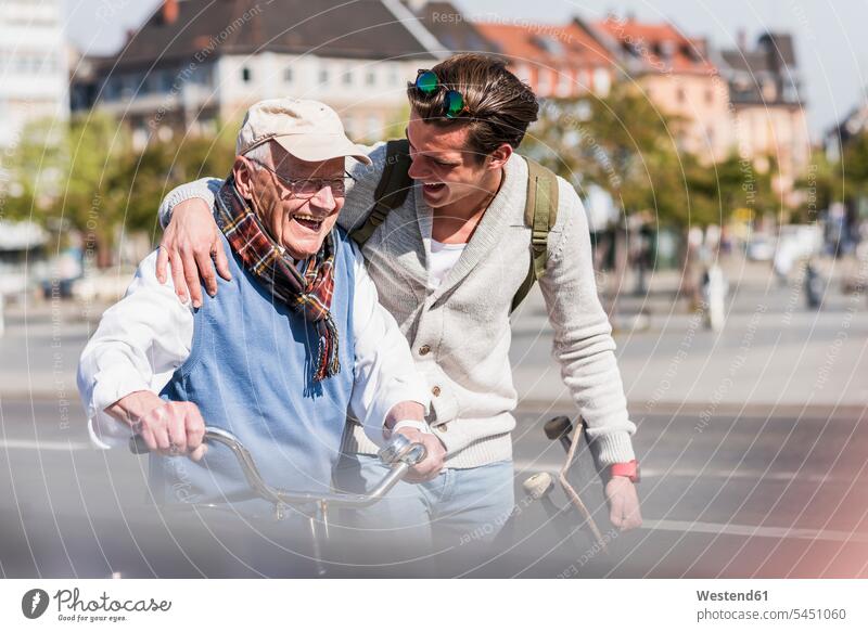 Happy senior man with adult grandson in the city on the move Fun having fun funny laughing Laughter grandfather grandpas granddads grandfathers grandsons