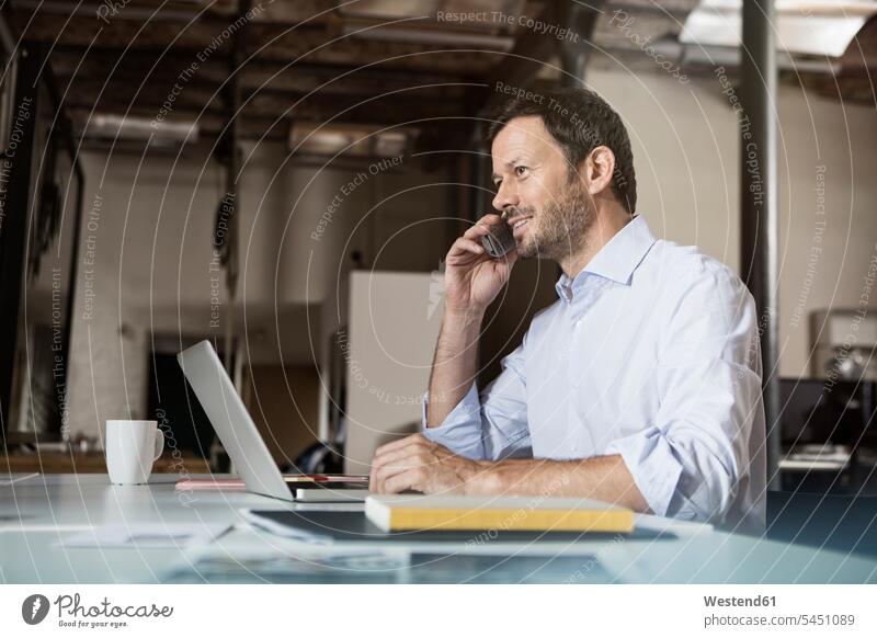 Businessman at desk with laptop and phone Laptop Computers laptops notebook on the phone call telephoning On The Telephone calling office offices office room