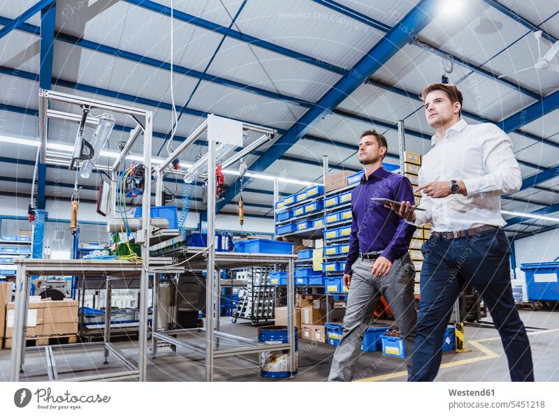 Two business people walking through shop floor. holding digital tablet discussing discussion businesspeople digitizer Tablet Computer Tablet PC Tablet Computers