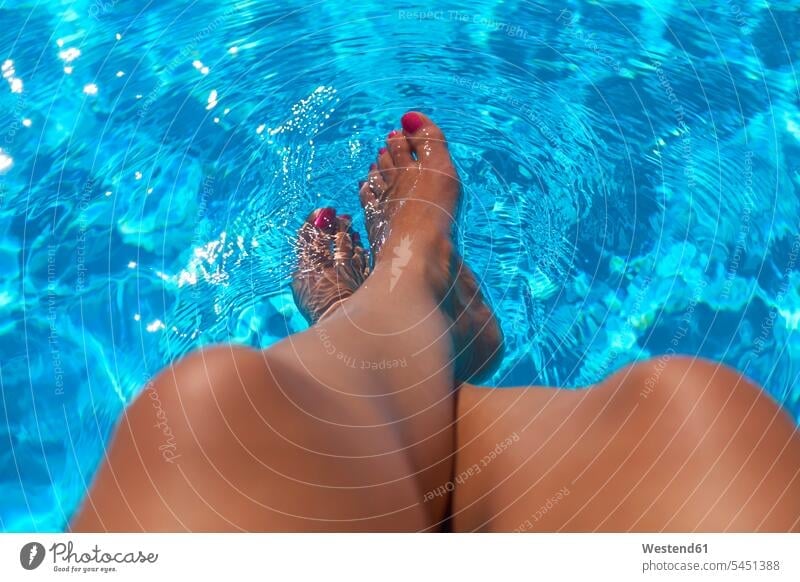 Woman Sitting At Pool Edge With Legs In The Water A Royalty Free