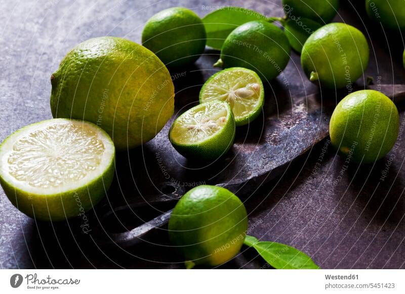 Sliced and whole limequats, limes, leaves and old knife on rusty ground nobody Fruit Fruits Citrus Fruit Citrus Fruits large group of objects many objects Lime