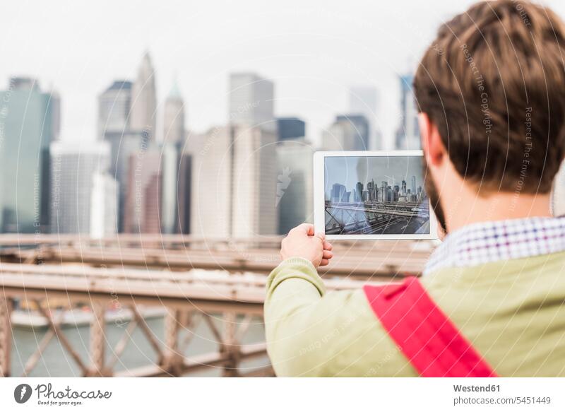 USA, New York City, man on Brooklyn Bridge taking tablet picture men males New York State photographing Adults grown-ups grownups adult people persons