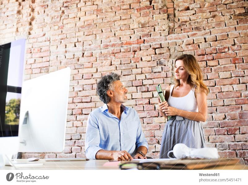 Two colleagues working together at desk in office desks At Work offices office room office rooms Table Tables workplace work place place of work work meeting