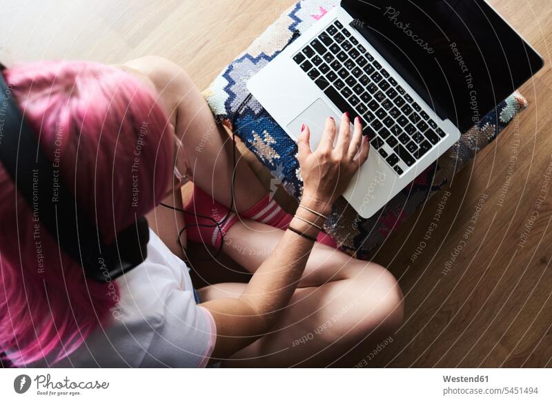 Young woman sitting on turquoise couch on terrace using laptop, top view -  a Royalty Free Stock Photo from Photocase