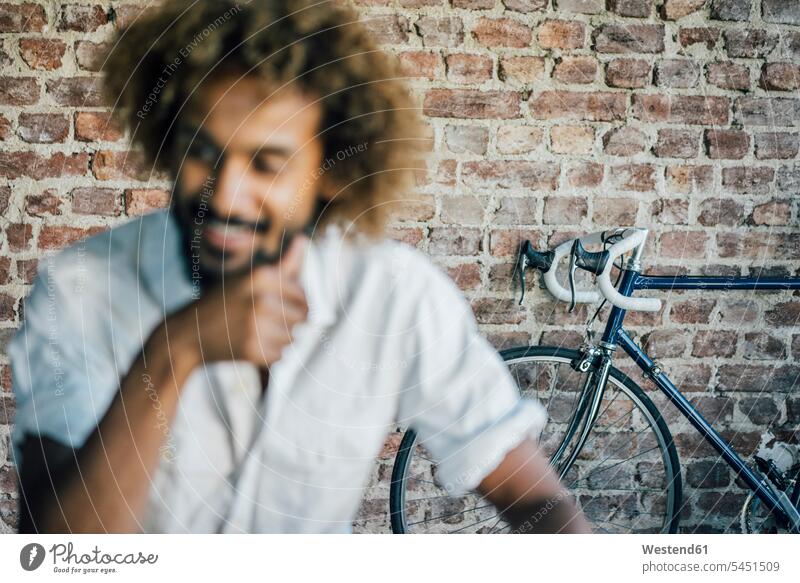 Smiling young man with bicycle in background smiling smile men males bikes bicycles Adults grown-ups grownups adult people persons human being humans