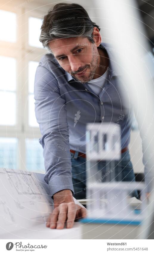 Man in office looking at architectural model man men males eyeing offices office room office rooms Businessman Business man Businessmen Business men Adults