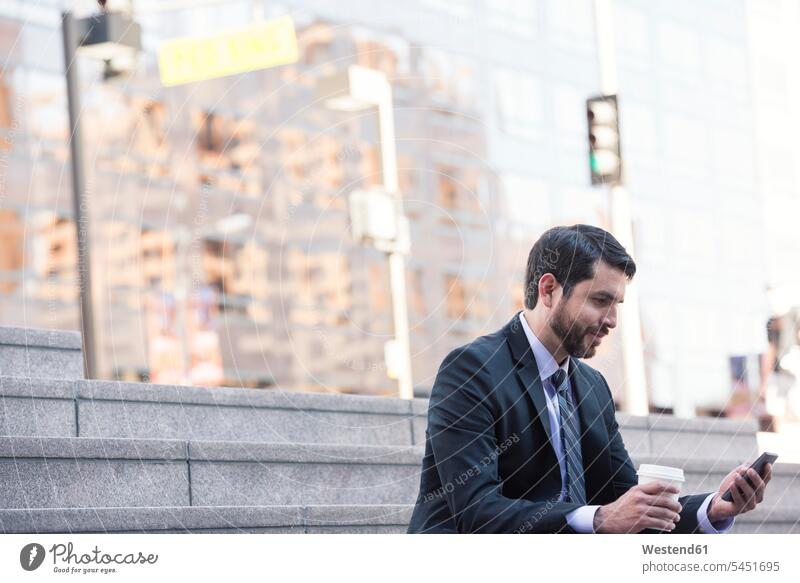 Businessman sitting on stairs with cell phone and takeaway coffee Business man Businessmen Business men stairway mobile phone mobiles mobile phones Cellphone