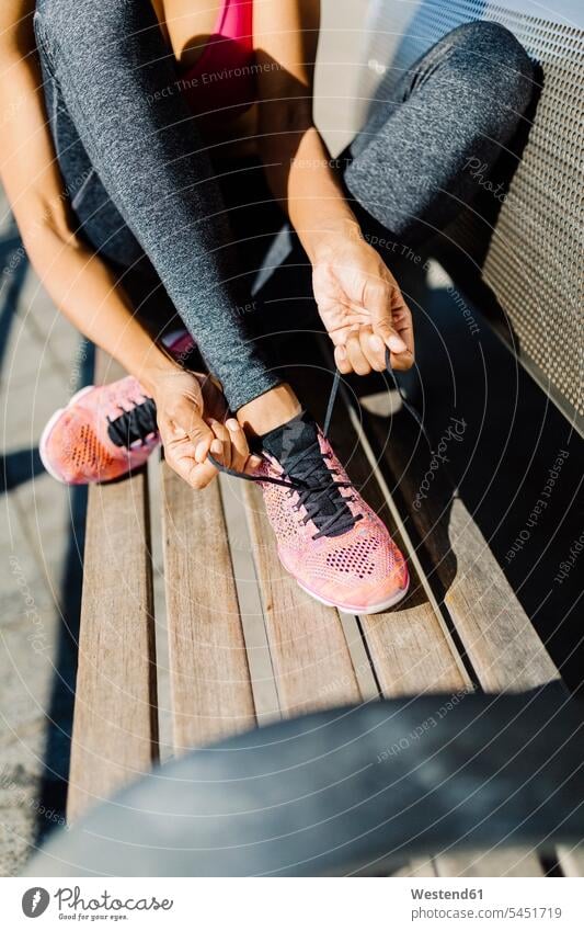 Female athlete sitting on ground tying her runners sportswoman athletes female athlete sportswomen female athletes running shoe running shoes females Seated