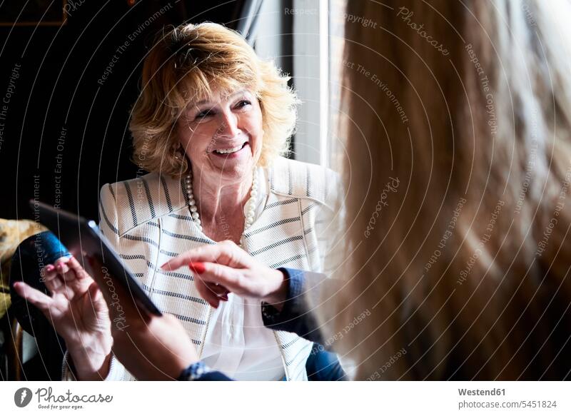 Two senior businesswomen with tablet having a meeting at a coffee shop smiling smile woman females digitizer Tablet Computer Tablet PC Tablet Computers iPad