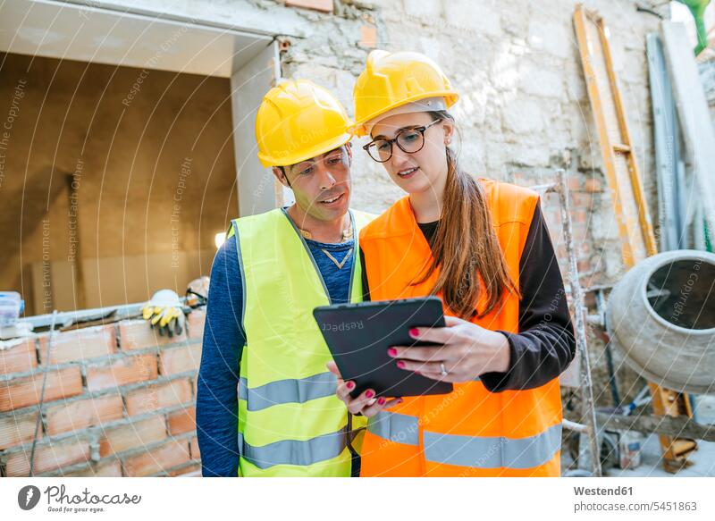 Woman With Tablet Talking To Construction Worker On Construction Site