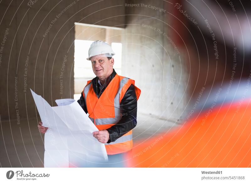 Two colleagues wearing safety vests and hard hats examining polystyrene - a  Royalty Free Stock Photo from Photocase