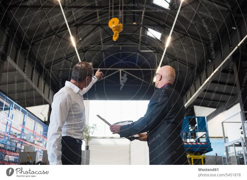 Two businessmen with clipboard on factory shop floor with bridge crane Businessman Business man Businessmen Business men factories business people