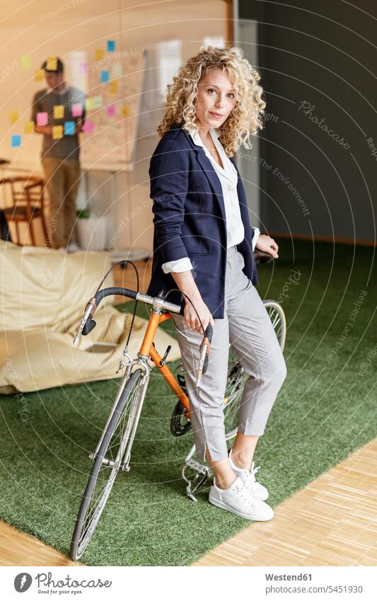 Portrait of woman with bicycle in office bikes bicycles Post it Post-it offices office room office rooms businesswoman businesswomen business woman