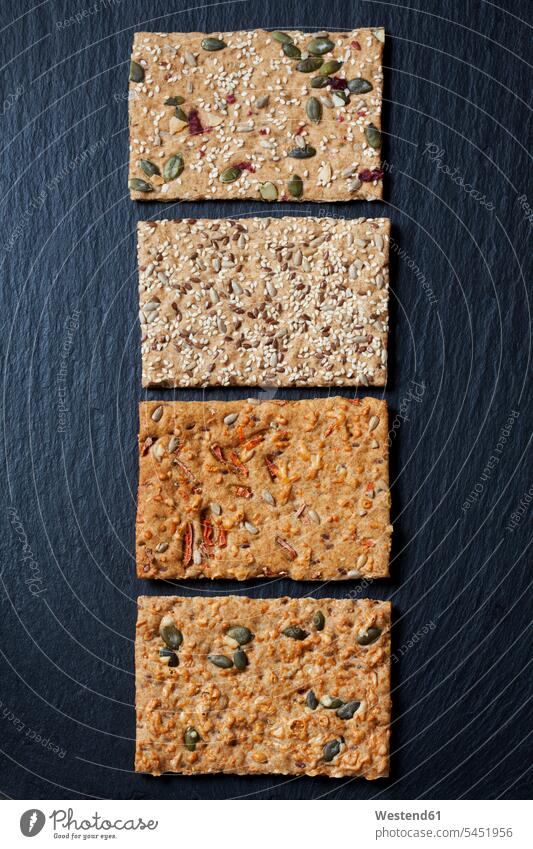 Row of four various slices of grain crispbreads on slate Carrot Carrots sunflower seed sunflower seeds rectangle Rectangles rectangular baked Baked Food